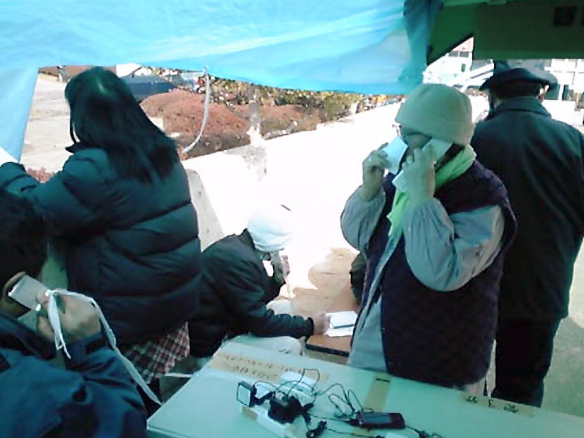 女川町総合グラウンドで行った、無料通話サービスの様子。設置翌日の朝には、より多くの人々に利用してもらえるよう、避難所で放送して告知した（2011年3月撮影）