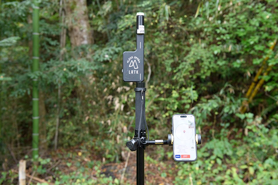 小型のGNSS受信機を取り付けたポール状のスタンドにスマートフォンを装着