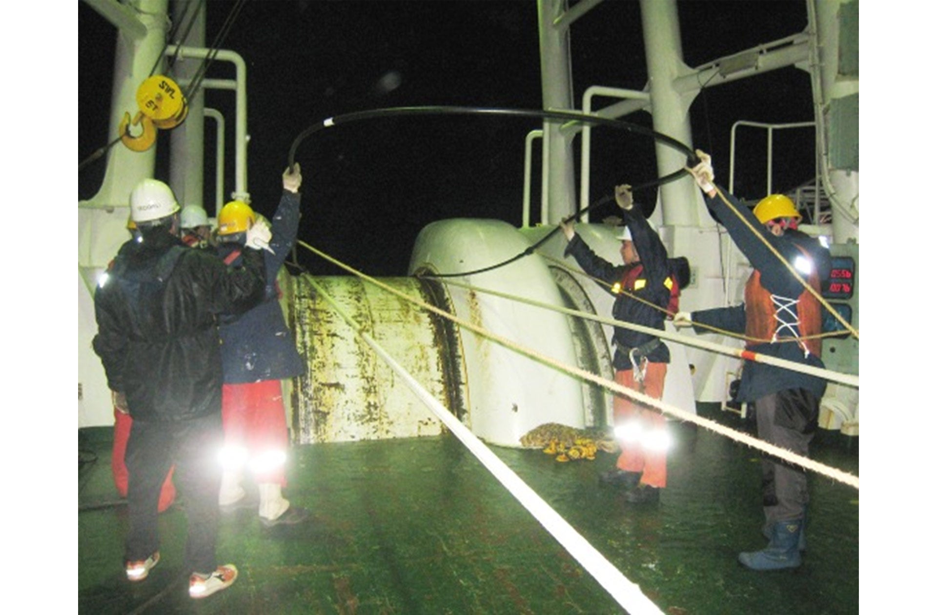 海中から回収したケーブルと船内の予備ケーブルを接続し、修理完了した最終接続部を海中に投入する模様（画像はKDDIケーブルインフィニティでの作業）